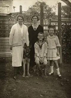 Alsatians: Four people with a German Shepherd dog in a garden