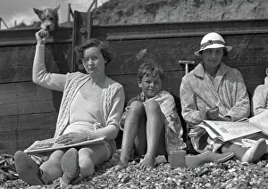 Pebbly: People leaning against a breaker on a beach