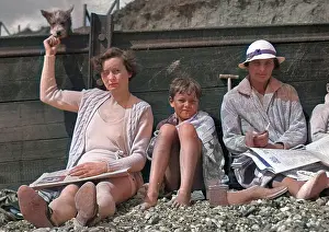 Pebbly: People leaning against a breaker on a beach