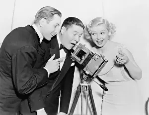 Formalwear: Three people looking through a camera and laughing
