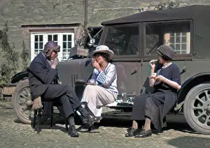 Picnicking: Three people picnicking at the side of a car