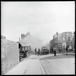 Demolishing: People standing, watching the demolition of houses