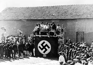 Willing: Before a podium decorated with a swastika flag an