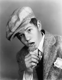 Startling: Portrait of a boy with a hat eating a candy bar