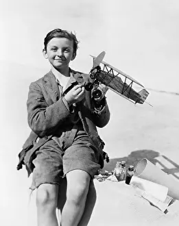 Ripped: Portrait of a boy holding a model airplane and smiling