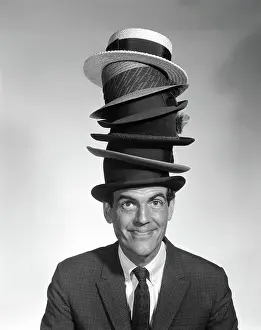 Businesspeople: Portrait of man looking at camera wearing 6 hats