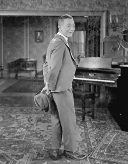 Caller: Portrait of man in suit holding hat