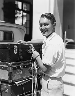 Securing: Portrait of man tying down luggage