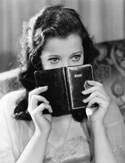 Reminiscence: Portrait of a young woman holding a diary and thinking