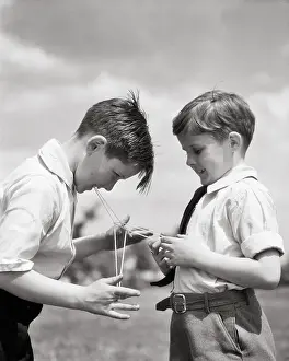 Preteen: Two Preteen Boys Playing with Loop of String Competing