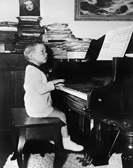 Naive: Profile of a boy sitting on a stool and playing a piano