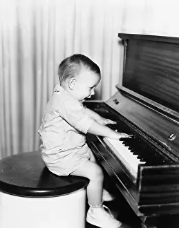 Naive: Profile of a little boy sitting on a stool and playing