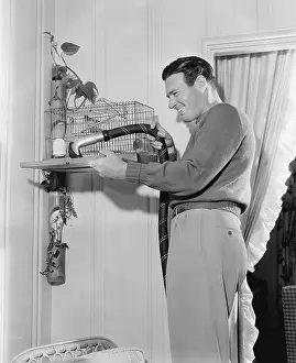 Avian: Profile of a man cleaning a cage with a vacuum cleaner