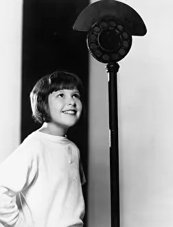 Waist Up: Profile of a young girl looking at a microphone and smiling