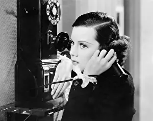 Seriousness: Profile of a young woman talking on a payphone
