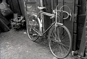 Bicyle: A Racing Bicyle leaned up against the fence in a back yard