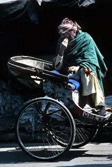 Ragged: A ragged driver sits on his cycle rickshaw, India