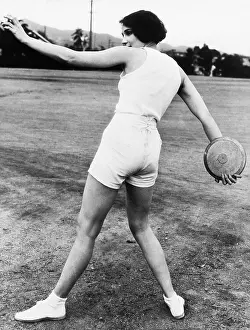Vigorous: Rear view of a young woman throwing a discus