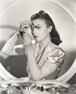Eyebrow: Reflection of woman in mirror applying eye make-up