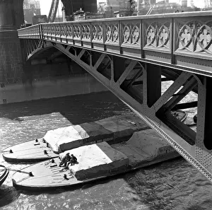 Dockworkers: River barges and dockworkers towed under Tower Bridge, Londo
