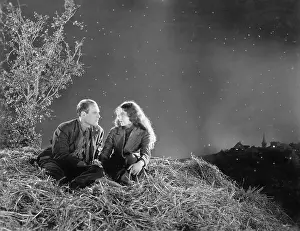 Nightfall: Romantic couple sitting on a stack of hay under the stars