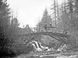 Unsharp: A rustic wooden bridge over a river and two men on it (unsha
