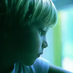 Abused: Sad Blond Boy with a Tear in his Eye Looking Out Window