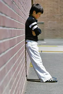 Outcast: Sad Boy Standing Against Brick Wall in School Playground