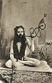 Asceticism: A Sadhu smoking a remarkable pipe, India