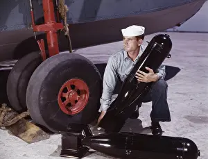Tire: Sailor picking up a bomb at Naval Air Base