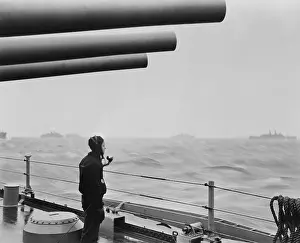 Conveys: A sailor on a warship keeps alert watch over merchant
