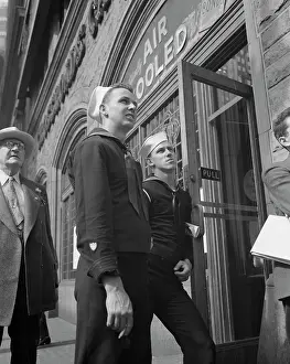 Spectator: Two sailors looking at a news line on a building
