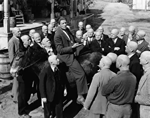 Intent: Salesman on donkey with group of bald men