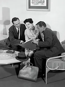 Salesperson: Salesman showing folder to couple at home in