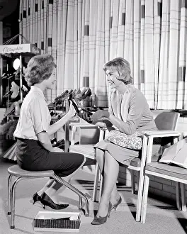 Saleswomen: Saleswoman Sitting on Stool Helping Customer Select