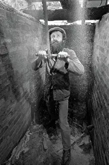 Sawing: The bottom sawyer in a saw pit cutting a timber log into pla