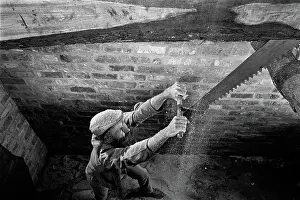 Sawing: Sawyer in a saw pit cutting a timber log into planks