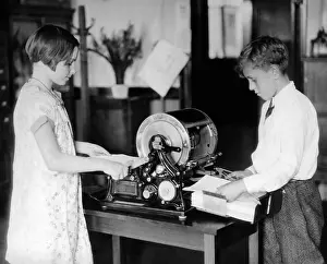 Patents: School children work on a mimeograph machine. ?