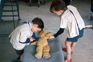 Injection: Two schoolboys give first aid to a teddy bear