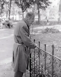 Disadvantaged: Senior Man Vagrant Leaning on Railing in City