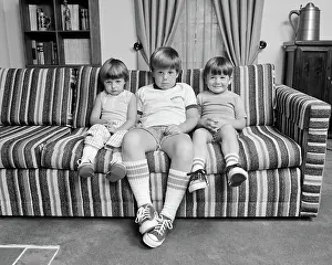Genes: Three Siblings Sitting on Couch Looking at Camera