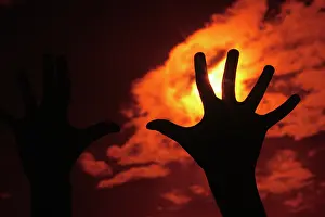 Strive: Single Silhouetted Hand Reaching Up into Orange Sky Graspi