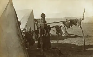 Lakota: Sioux woman standing between two frames on which