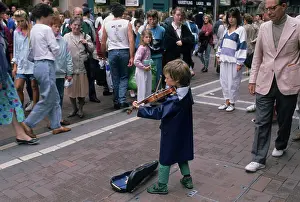 Fiddle: Small boy busking with his violin for an audience in Dublin