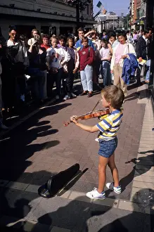 Fiddle: Small boy busking with his violin for an audience in Dublin