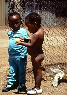 Squatter: Two small children stand in front of a wire mesh