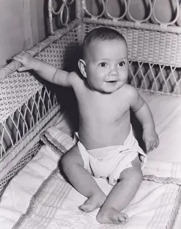 Diaper: Smiling baby boy sitting in crib