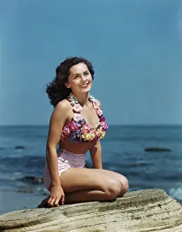 Two Piece: Smiling bathing woman sitting on a rock