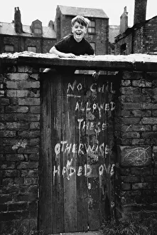 Climbs: Smiling boy climbs back yard gate - Manchester 1966