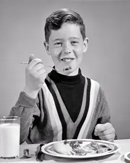 Preteen: Smiling Boy Looking at Camera Eating a Forkful